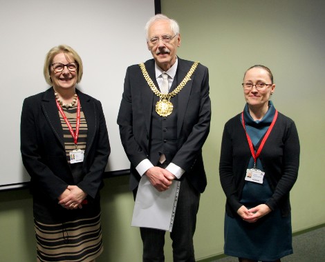 A male wearing mayoral chains stands in between two females.